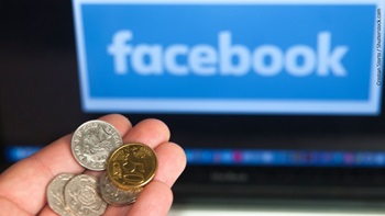 Facebook sul monitor e mano con monete